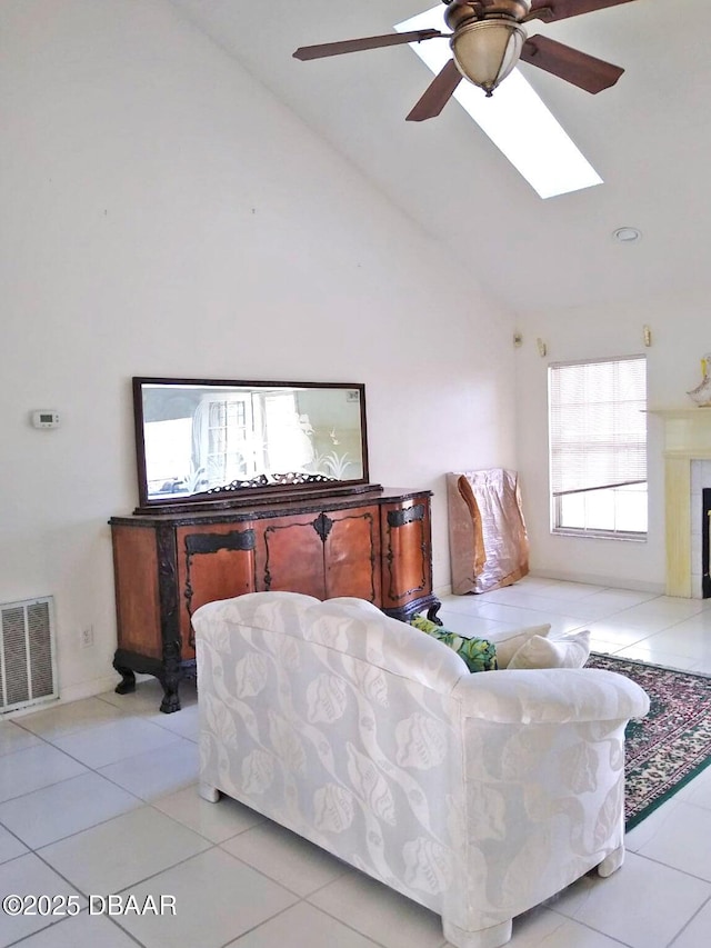 living room featuring light tile patterned floors, a skylight, and high vaulted ceiling