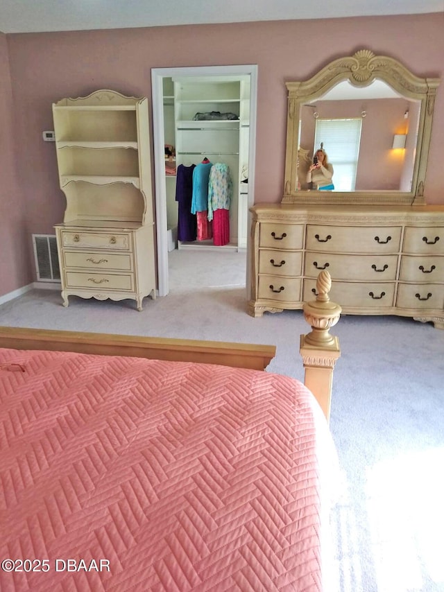 unfurnished bedroom with a walk in closet, light carpet, and a closet