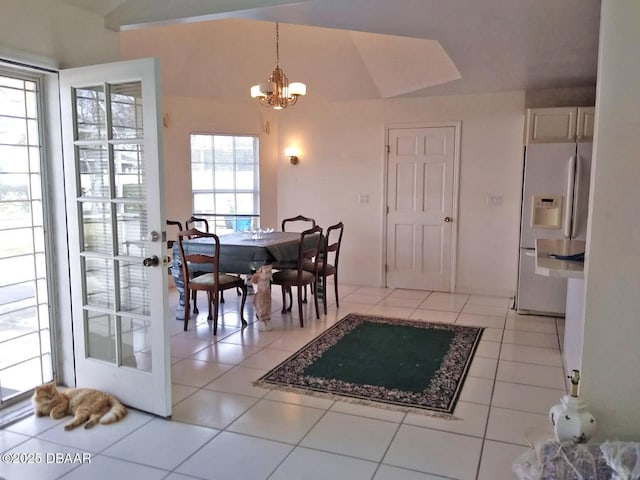 tiled dining area with lofted ceiling and a notable chandelier