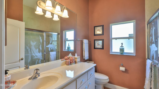 bathroom featuring vanity, toilet, and a shower with door