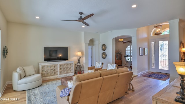 living room featuring light hardwood / wood-style flooring and ceiling fan with notable chandelier