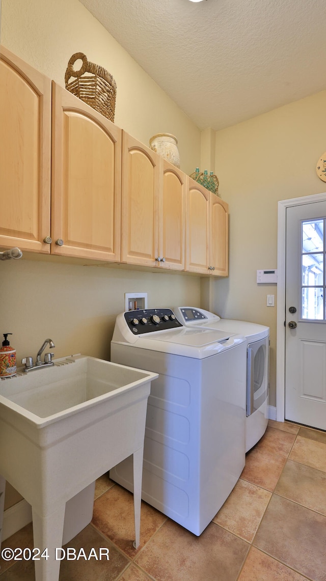 laundry area featuring cabinets, sink, washing machine and dryer, a textured ceiling, and light tile patterned flooring