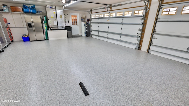 garage with heating unit, a garage door opener, and stainless steel refrigerator with ice dispenser