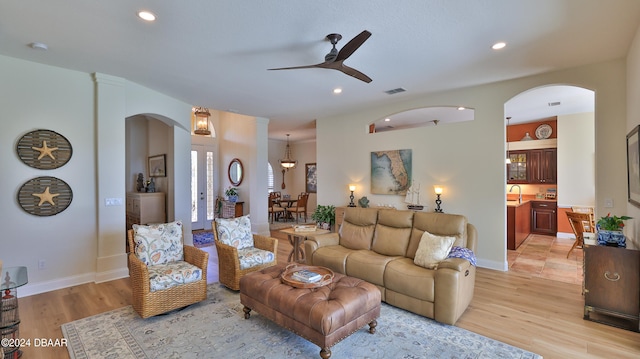 living room featuring light wood-type flooring, ceiling fan, and sink