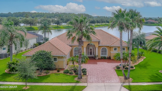 mediterranean / spanish house featuring cooling unit, a front lawn, and a water view