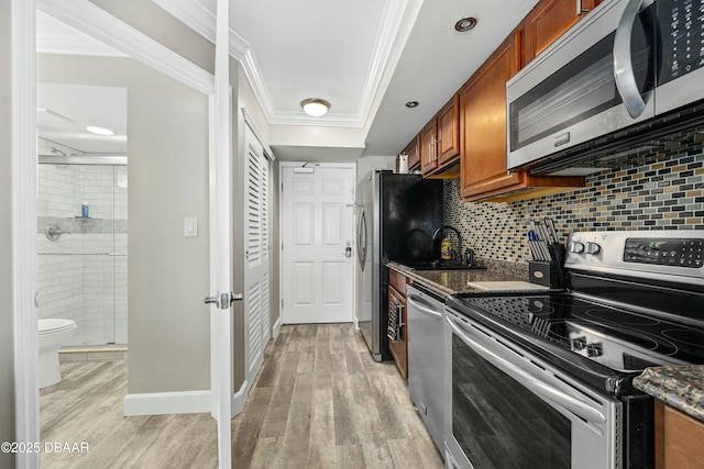 kitchen featuring backsplash, ornamental molding, light hardwood / wood-style floors, and appliances with stainless steel finishes