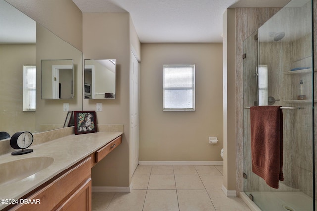 bathroom featuring toilet, vanity, tile patterned flooring, and a shower with shower door