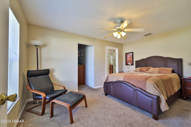 carpeted bedroom featuring connected bathroom, a textured ceiling, and ceiling fan