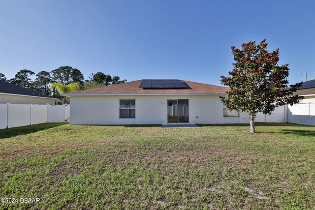 rear view of house with solar panels and a lawn