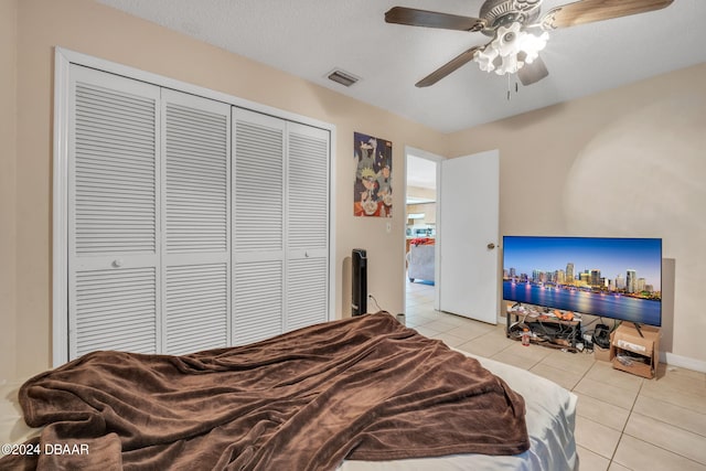 bedroom with ceiling fan, a textured ceiling, light tile patterned floors, and a closet