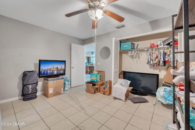 tiled living room featuring ceiling fan and a textured ceiling