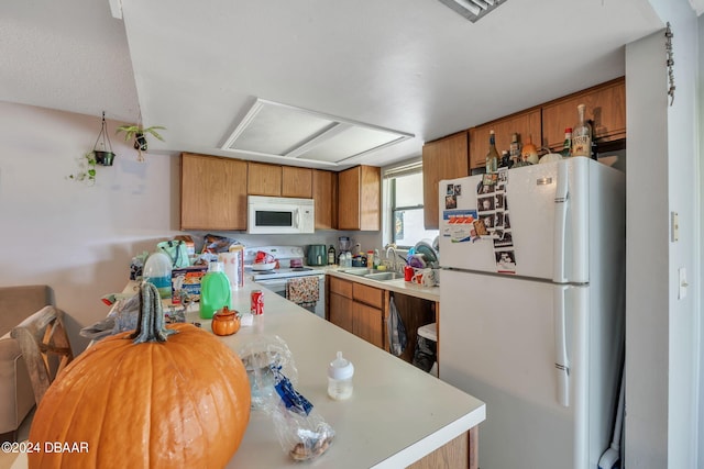 kitchen featuring kitchen peninsula, white appliances, and sink