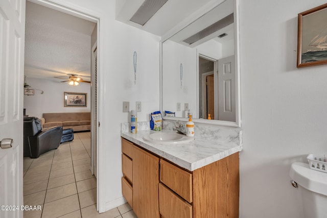 bathroom with toilet, tile patterned flooring, a textured ceiling, vanity, and ceiling fan