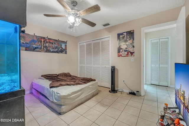 tiled bedroom with a textured ceiling and ceiling fan