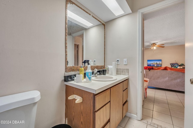 bathroom featuring toilet, tile patterned flooring, a textured ceiling, vanity, and ceiling fan