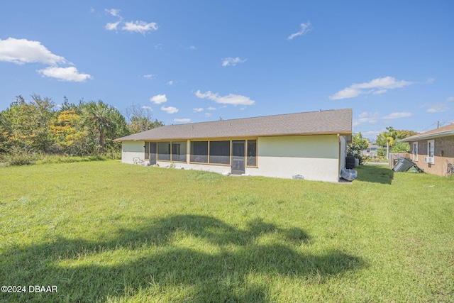 back of property featuring a lawn and a sunroom