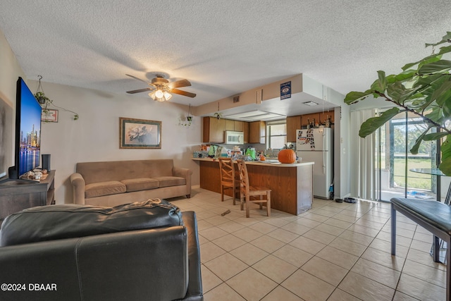 tiled living room featuring ceiling fan and a textured ceiling