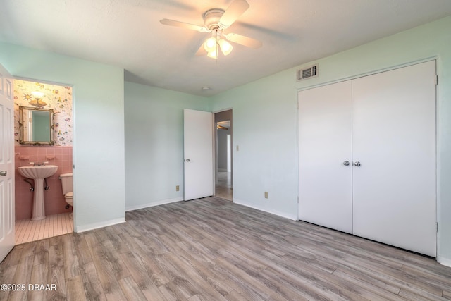 3622 Ocean Shore Blvd, Ormond Beach, FL 32176 - unfurnished bedroom featuring wood finished floors, ensuite bath, a closet, and a ceiling fan