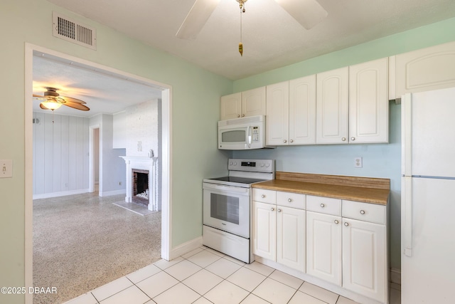 3622 Ocean Shore Blvd, Ormond Beach, FL 32176 - kitchen featuring white appliances, a ceiling fan, white cabinets, and a fireplace with raised hearth