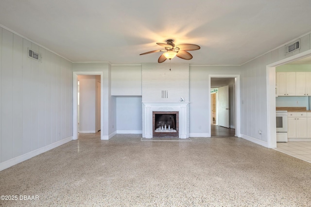 3622 Ocean Shore Blvd, Ormond Beach, FL 32176 - unfurnished living room featuring ceiling fan, dark speckled floor, crown molding, and a large fireplace