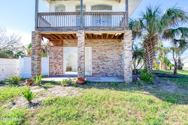 rear view of house with a balcony and a yard