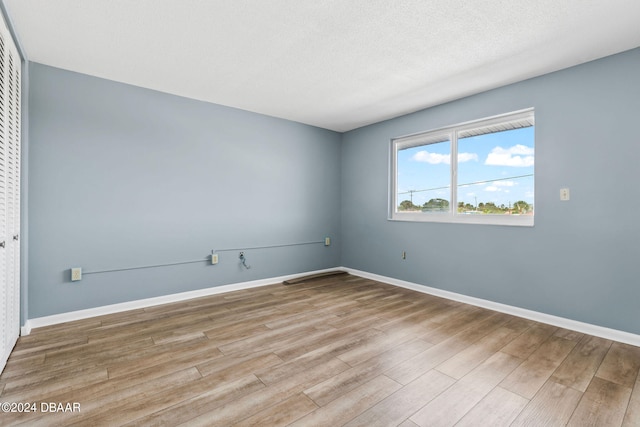 unfurnished room featuring a textured ceiling and light hardwood / wood-style floors