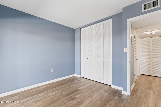 unfurnished bedroom with light wood-type flooring and a closet