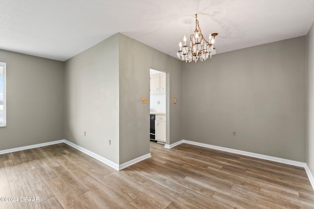 empty room with hardwood / wood-style flooring and an inviting chandelier