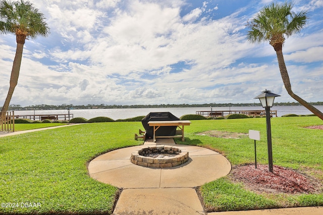 surrounding community featuring a lawn, a water view, and a fire pit