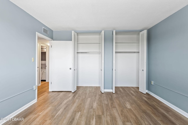 unfurnished bedroom featuring light hardwood / wood-style floors and two closets