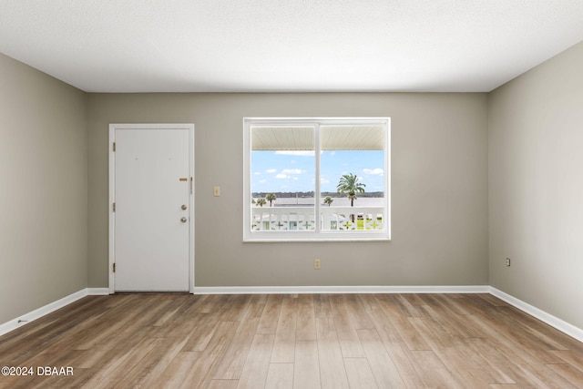 spare room featuring a textured ceiling and light hardwood / wood-style floors