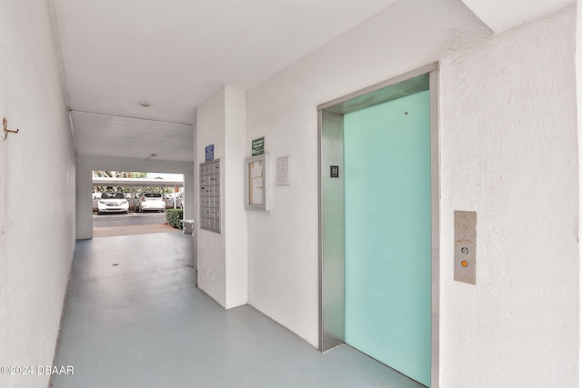 hall featuring a mail area, concrete flooring, and elevator