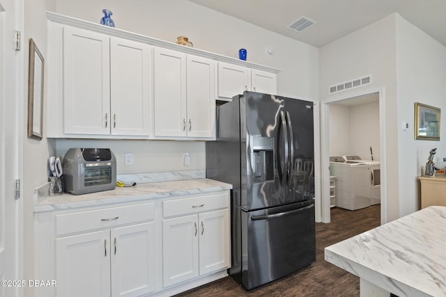 kitchen featuring dark hardwood / wood-style flooring, stainless steel fridge with ice dispenser, washer and clothes dryer, and white cabinets