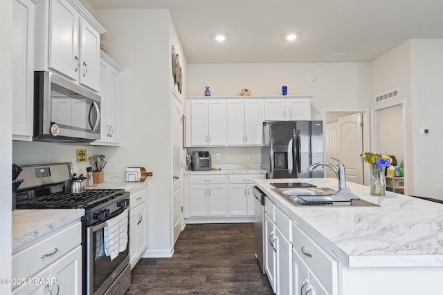 kitchen featuring white cabinets, dark hardwood / wood-style flooring, a kitchen island with sink, and appliances with stainless steel finishes