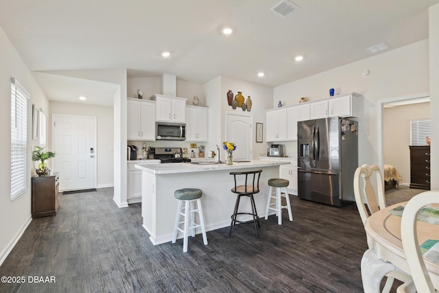 kitchen with white cabinets, a breakfast bar, an island with sink, and stainless steel appliances