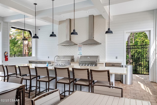 kitchen with tasteful backsplash, a breakfast bar, and wall chimney exhaust hood