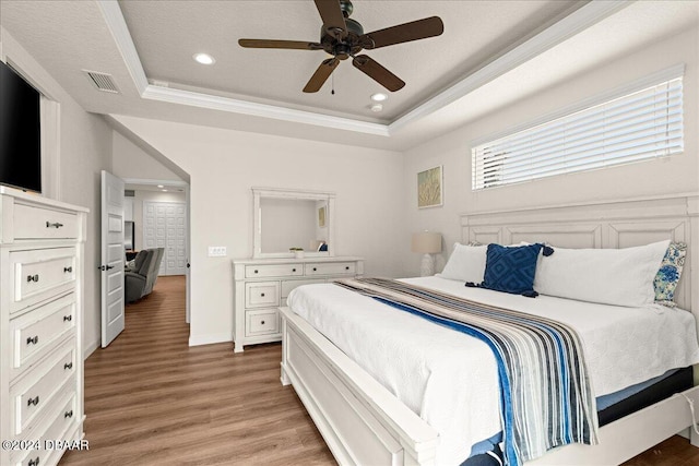 bedroom featuring ceiling fan, a raised ceiling, and wood-type flooring