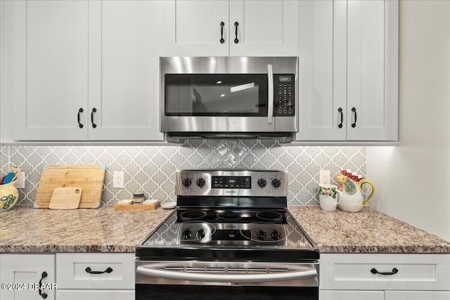 kitchen featuring stainless steel appliances, white cabinetry, light stone counters, and tasteful backsplash