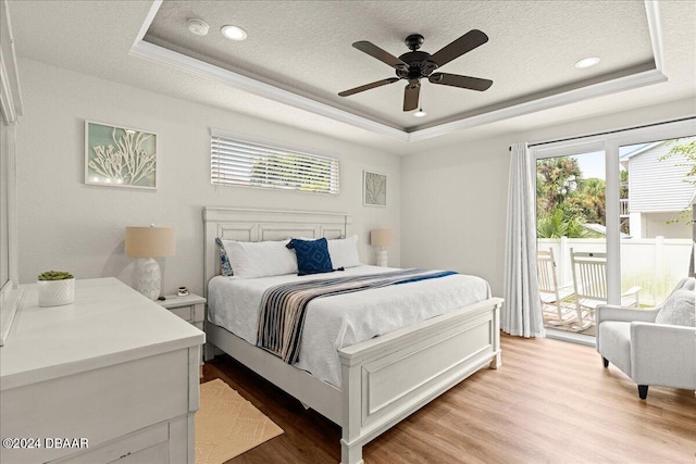 bedroom featuring light hardwood / wood-style floors, ceiling fan, and a tray ceiling