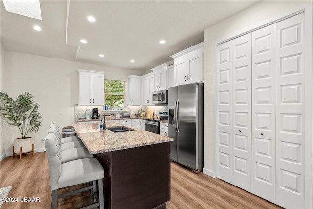 kitchen with a center island, white cabinets, light hardwood / wood-style floors, and stainless steel appliances