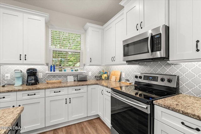 kitchen with appliances with stainless steel finishes, light stone countertops, decorative backsplash, light hardwood / wood-style floors, and white cabinets