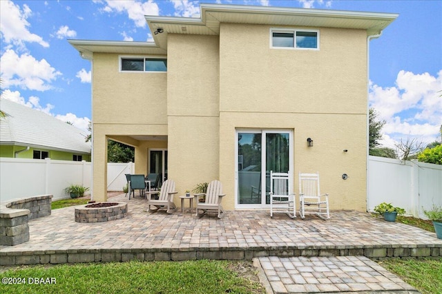 rear view of property with a fire pit and a patio