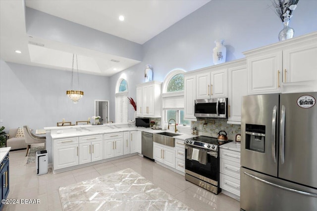 kitchen featuring sink, kitchen peninsula, appliances with stainless steel finishes, light tile patterned floors, and white cabinets