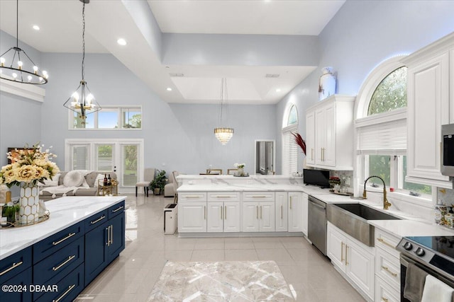 kitchen featuring hanging light fixtures, a towering ceiling, appliances with stainless steel finishes, and blue cabinets