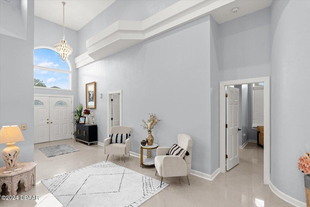 tiled entryway with a towering ceiling and a chandelier