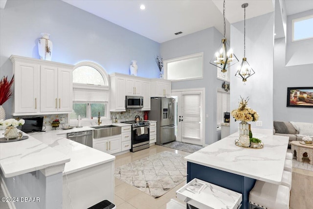 kitchen with white cabinetry, appliances with stainless steel finishes, pendant lighting, a wealth of natural light, and sink