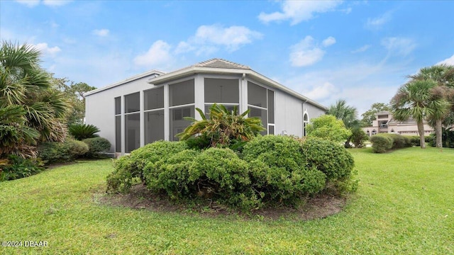 view of side of home with a lawn and a sunroom