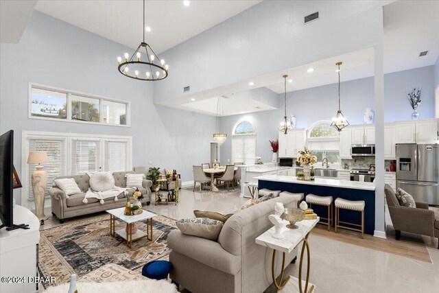 tiled living room featuring a high ceiling, sink, a wealth of natural light, and a chandelier