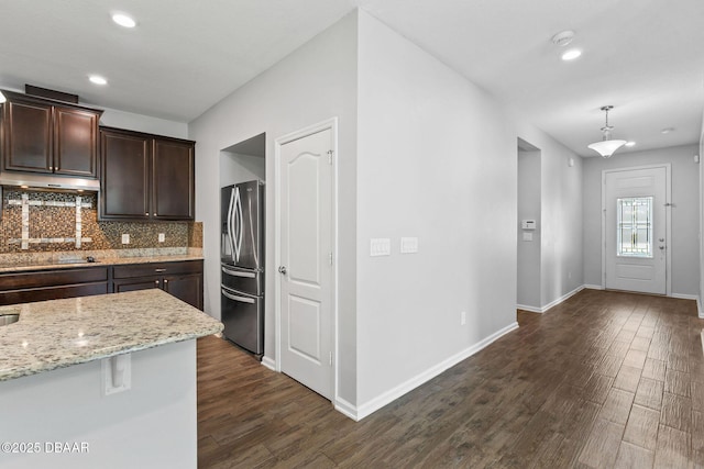 115 Pergola Pl, Ormond Beach, FL 32174 - kitchen featuring stainless steel refrigerator with ice dispenser, dark wood-style floors, dark brown cabinets, decorative backsplash, and light stone countertops