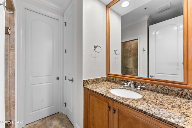 full bathroom with vanity, ornamental molding, a tile shower, and visible vents